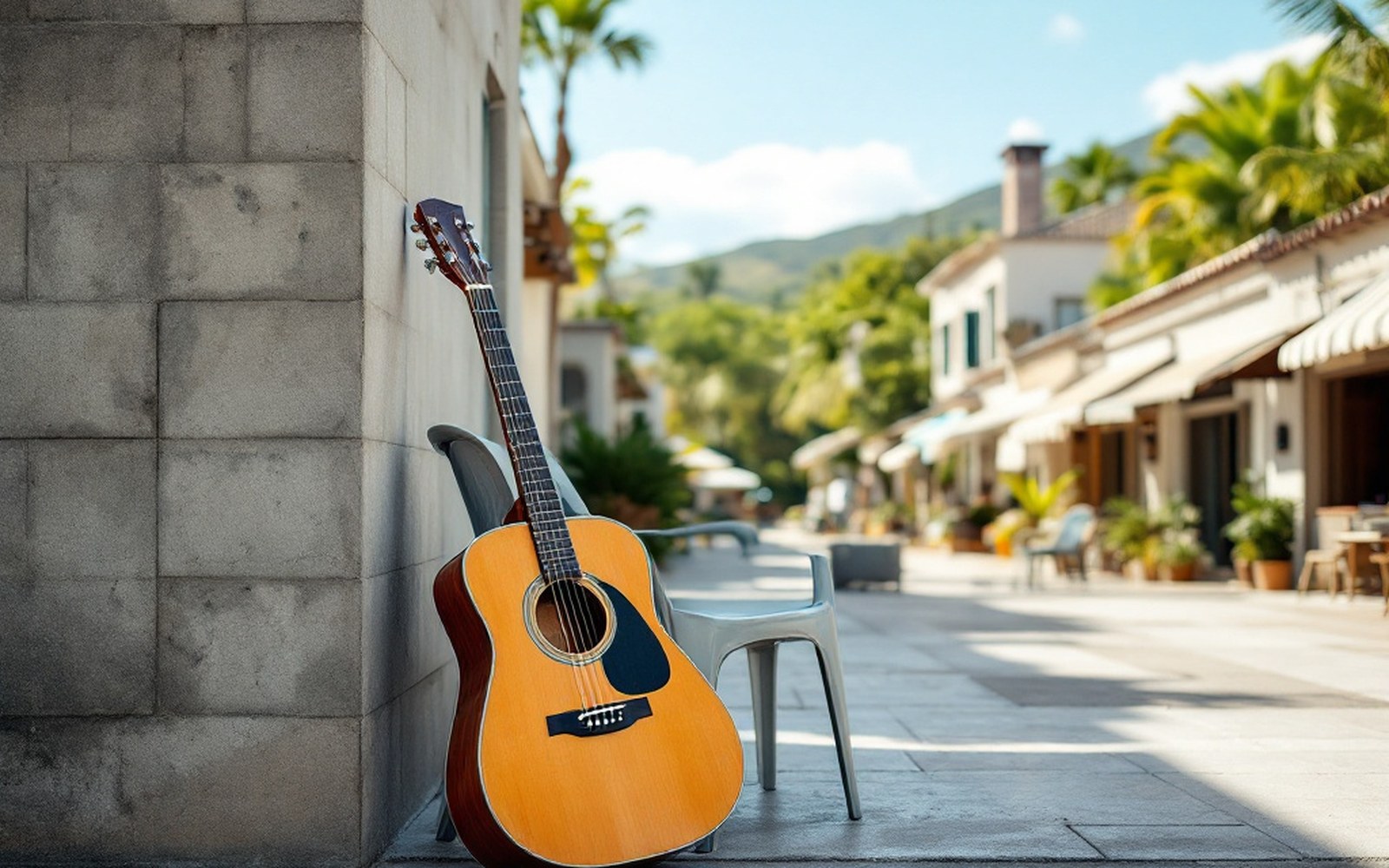 An acoustic guitar propped against a concrete wall beside a plastic chair